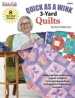 May include: A book titled 'Quick as a Wink 3-Yard Quilts' by Donna Robertson. The book cover features a woman sitting on a green chair with a purple and pink quilt. The book cover also includes a yellow star with the text '8 New Quilt Designs!'.