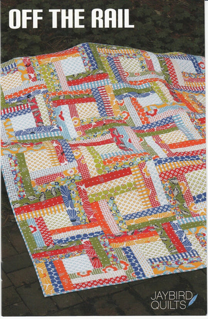 May include: A quilt with a log cabin pattern in red, orange, yellow, green, blue, and white fabrics. The quilt is on a brown surface. The text 'OFF THE RAIL' is at the top of the image. The text 'JAYBIRD QUILTS' is at the bottom of the image.