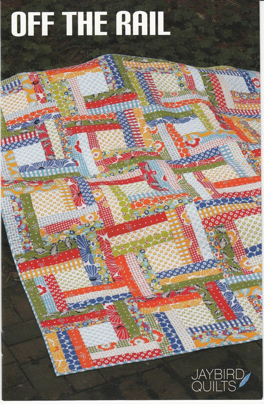 May include: A quilt with a log cabin pattern in red, orange, yellow, green, blue, and white fabrics. The quilt is on a brown surface. The text 'OFF THE RAIL' is at the top of the image. The text 'JAYBIRD QUILTS' is at the bottom of the image.