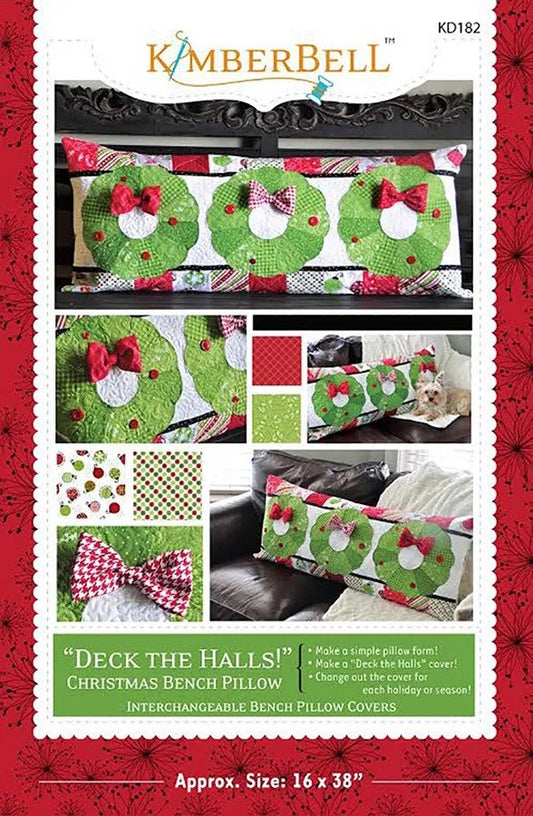 May include: A sewing pattern for a Christmas bench pillow with interchangeable covers. The pattern features a green wreath design with red bows and buttons. The text on the pattern reads 'Deck the Halls!' Christmas Bench Pillow. Interchangeable Bench Pillow Covers. Approx. Size: 16 x 38'.
