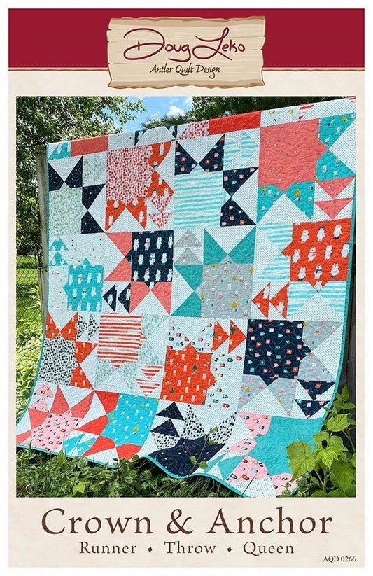 May include: Crown & Anchor quilt pattern by Doug Leko Antler Quilt Design. The quilt is made in a variety of colors including teal, coral, white, black, and gray. The quilt is displayed on a wooden fence with green foliage in the background. The quilt pattern is a mix of stars, squares, and triangles. The text on the pattern reads 'Crown & Anchor', 'Runner', 'Throw', 'Queen', and 'AQD 0266'.