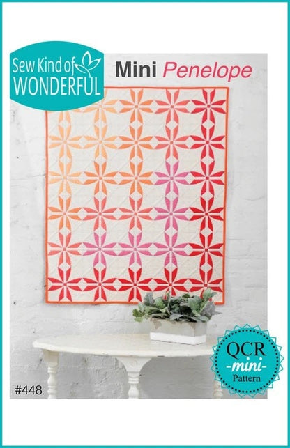 May include: Mini Penelope quilt pattern with a red, orange, and pink color scheme. The pattern is called 'Mini Penelope' and is a 'mini' pattern. The pattern number is #448. The pattern is from Sew Kind of Wonderful.