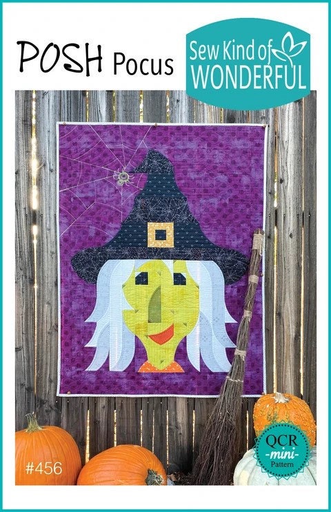 May include: A purple and white quilt with a witch design. The witch has a black hat, white hair, and a green face. The quilt is hanging on a wooden fence with a broom and pumpkins in the foreground. The text on the quilt reads 'Sew Kind of Wonderful' and 'Posh Pocus'. The text below the quilt reads '#456' and 'QCR -mini- Pattern'.