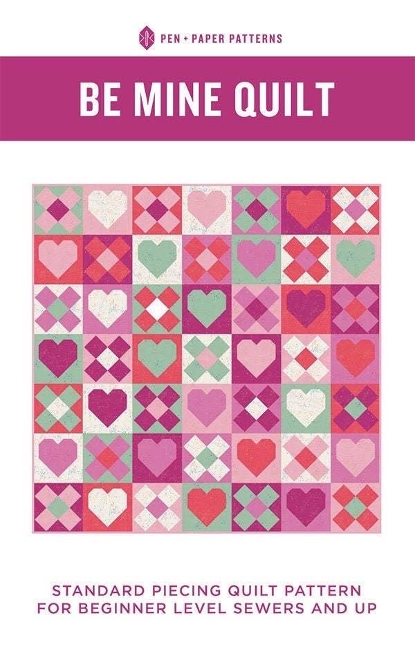 May include: A quilt pattern featuring a patchwork design of pink, red, and green hearts and squares. The pattern is titled "Be Mine Quilt" and is described as a standard piecing quilt pattern for beginner level sewers.