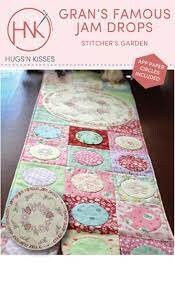 May include: A table runner featuring a patchwork design with circles of various colors and patterns. The runner is made of fabric and has a pink, green, and blue color scheme. The text "Gran's Famous Jam Drops" is printed on the image.
