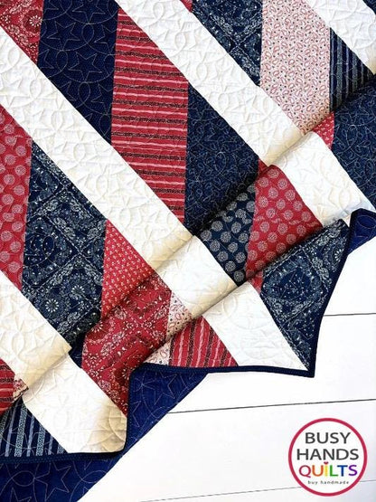 May include: A red, white, and blue chevron quilt with a star pattern quilted into the white fabric. The quilt is folded in half and the fabric is made of cotton. The quilt is handmade by Busy Hands Quilts.